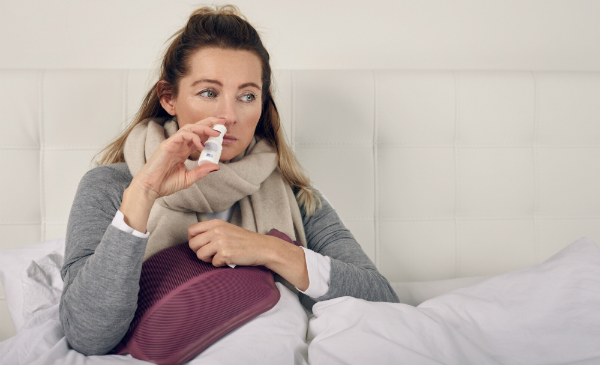Frau mit Krankheit benutzt ein Nasenspray, um die Schleimhäute zu befeuchten