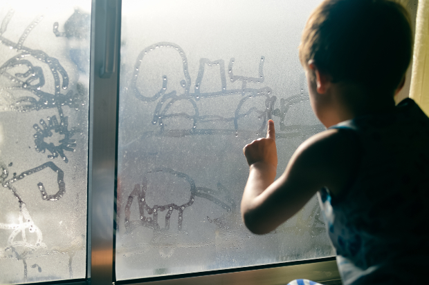 Junge am malt auf kondensiertem Fenster