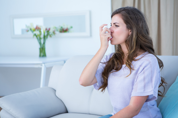 Frau mit Asthma Spray - roter Schimmel kann Asthma auslösen