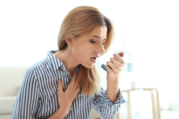 Frau mit Asthma Spray - Luftfeuchtigkeit im Bad kann Schimmel befördern