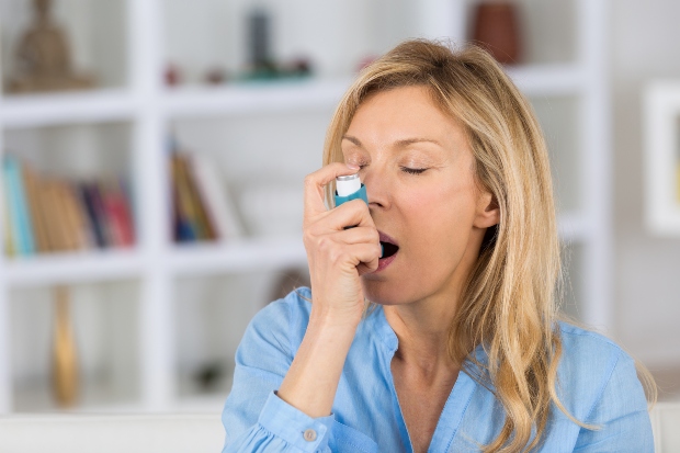Frau inhaliert mit Asthma Spray