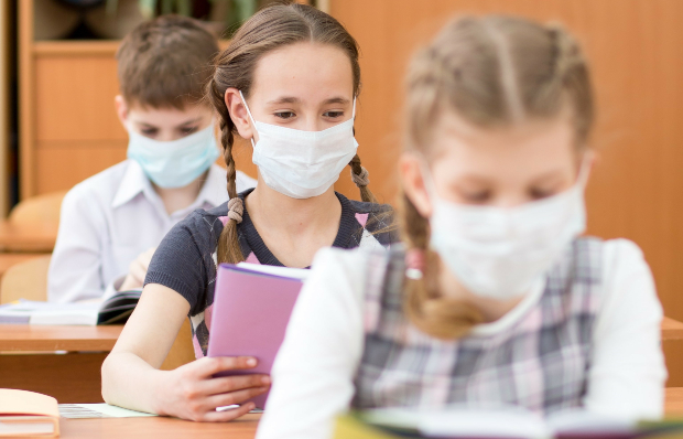 Junge Schüler im Klassenzimmer mit Mund-Nase-Schutzmasken - Aerosole können sich so schlechter verbreiten