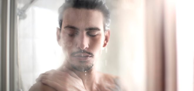 Mann duscht - Raumentfeuchtung im Bad