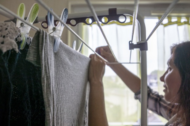 Kleidung in der Wohnung trocknen - Frau hängt Wäsche auf