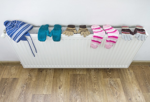 Socken, Handschuhe und Mütze liegen zum Trocknen auf einer Heizung - Kleidung in der Wohnung trocknen