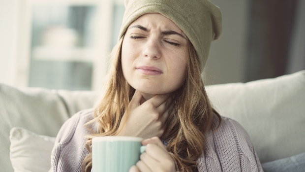 Herbst und Winter sind Erkältungszeit - ein Grund ist die tendenziell trockenere Luft Junge Frau fasst sich an den Hals - sie ist erkältet - häufig bei niedriger Luftfeuchtigkeit im Winter