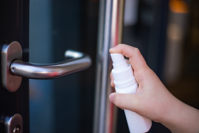 Someone sprays door handle with disinfectant spray - Reduce virus concentration through disinfection