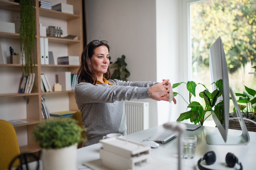 Junge Frau strecht im Home-Office